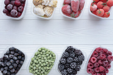 Top view of frozen berries in boxes on white wooden background with copy space