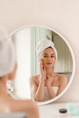 Young beautiful woman with silicone gold eye patches. Facial care at home. Girl with clean skin. Young beautiful girl cares for the skin using patches under the eyes at home.
