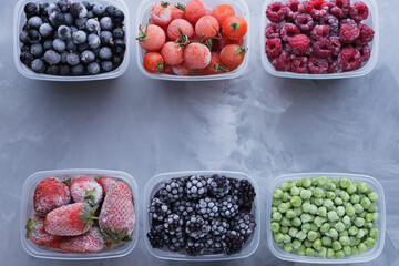 Top view of frozen berries in boxes on gray background with place for text