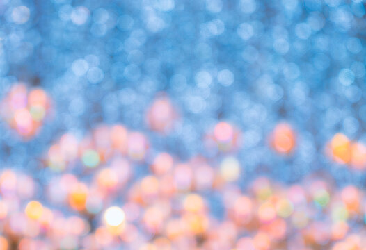 Blurred abstract bokeh background of lighting decoration from ceiling in theme of New Year celebration, lighting colour of blue, yellow, pink and orange. Blurred background space for copy and design.
