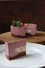 A piece of homemade mousse sweet pink cake on the plate. The concept of proper nutrition. A piece of cake on the foregraund and a cake blurred on the background.