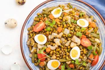 Mung bean porridge with quail eggs, tomatoes and microgreen sprouts on a white concrete background. Top view, close up.