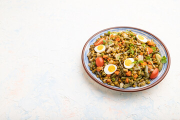 Mung bean porridge with quail eggs, tomatoes and microgreen sprouts on a white concrete background. Side view, copy space.