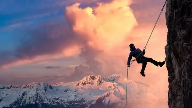 Cinemagraph Continuous Loop Animation. Epic Adventurous Extreme Sport Composite of Rock Climbing Man Rappelling from a Cliff. Mountain Landscape Background from British Columbia, Canada.