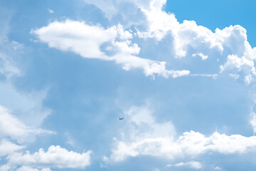 Airplane flying in the blue sky among clouds and sunlight