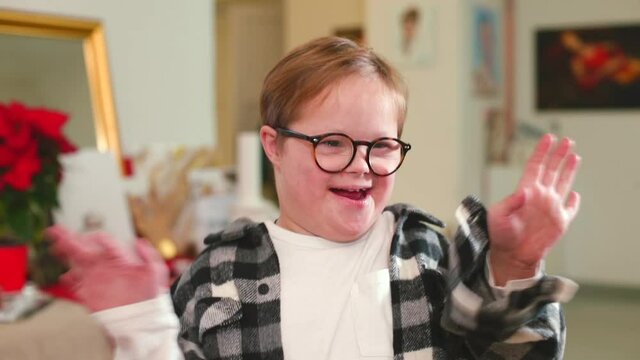 Portrait of a boy with special needs. He speaks, emotionally waving arms. Children with Down syndrome have difficulty with grammar, tenses and word endings and use shorter sentences to communicate.