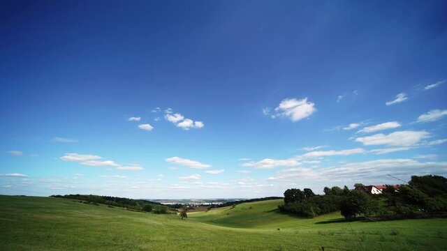 Time lapse of rolling clouds on blue sky over green field background