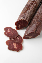 Dried sausage sliced into slices on a white plate. Elite meat product