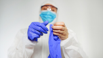 Medical worker in protective suit puts on gloves.