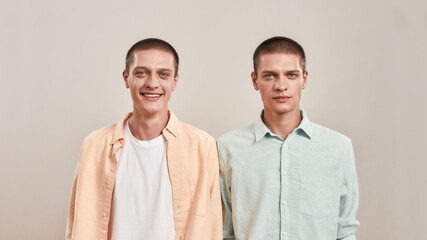 Portrait of two young twin brothers wearing casual clothes looking at camera at camera while posing...