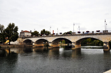 Fototapeta na wymiar View of the Charente River. And a stone bridge across the river. Arched bridge NEF.