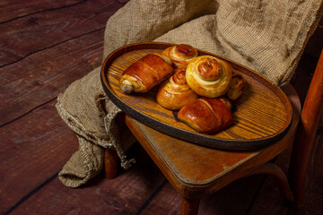 Homemade buns on a wooden tray. Home kitchen. A tray of buns on a wooden stool.