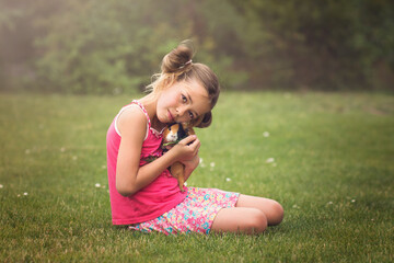 Young girl cradle guinea pig pet in her arms in the garden. Child and animal concept.