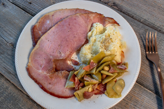 rustic Thanksgiving plate of baked ham with mash potatoes and green beans flat lay