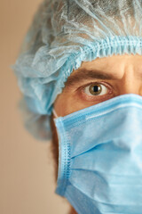 Close up portrait of a doctor in a medical mask. Portrait of a young European male doctor wearing a medical cap and medical mask. Security measures against coronavirus.