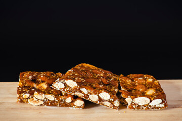 Turrón de guirlache con almendras, dulce típico español, sobre madera y fondo negro