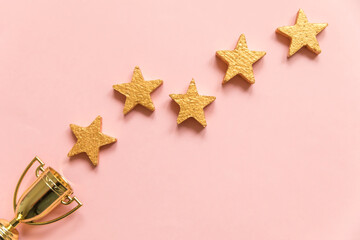 Simply flat lay design winner or champion gold trophy cup and 5 stars rating isolated on pink...