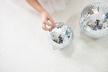 Close-up picture of small girl's hands playing with silver christmas balls on white background. Happy new year celebration party.