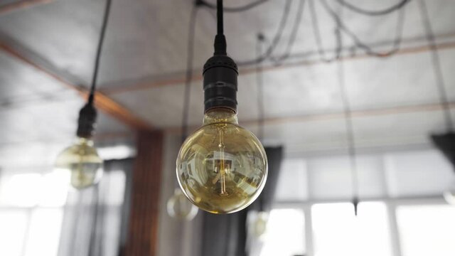 Big vintage incandescent light bulbs hanging in modern kitchen. Decorative antique edison light bulbs with straight wire. Inefficient filament light bulbs waste electricity. Warm white, dimmable, E27