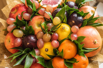 Fruit bouquet of apples, lemons, plums, grapes, tangerines, grapefruit and green leaves