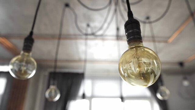 Decorative antique edison light bulbs with straight wire. Big vintage incandescent light bulbs hanging in modern kitchen. Inefficient filament light bulbs waste electricity. Dimmable, warm white, E27