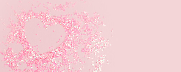 Heart shape made of Pink holiday confetti on pink background. Minimal idea concept. Saint Valentine...