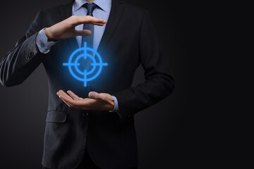 Targeting concept with businessman hand holding target icon dartboard sketch on chalkboard. Objective target and investment goal concept.