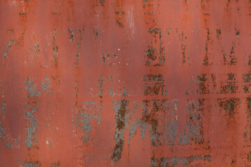 The background of a peeling and rusty iron wall is red