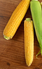 Fresh corn on cobs on rustic wooden table.