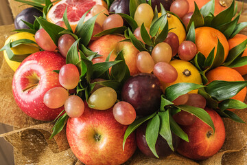 Fruit bouquet of apples, lemons, plums, grapes, tangerines, grapefruit and green leaves
