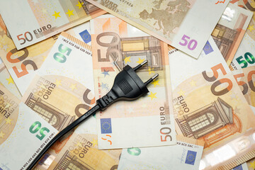 Black power plug on euro banknotes. Expensive energy and cost of electricity concept.