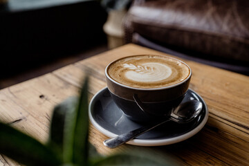 Cup of hot Cappuccino coffee on wooden table at cafe. with Cake Fresh invigorating drink