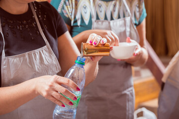 Pouring liquid from a measurer into a bottle.