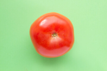 Red tomato on green background. Single vegetable, healthy eating concept.