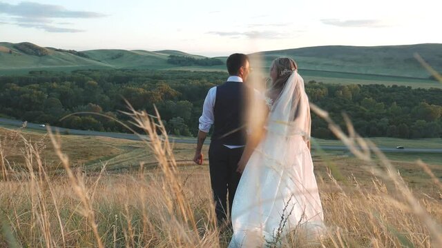 The bride and groom are walking against the background of the mountains
