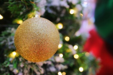 Golden ball, decoration of Christmas tree and lighting. Selective focus with bokeh of christmas tree background. Christmas and happy new year background concept.