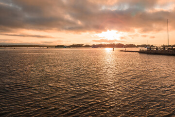 Beautiful sunset over a bay in autumn. Anchored boats are visible in distance. Falmouth, Cape Cod, MA, USA.