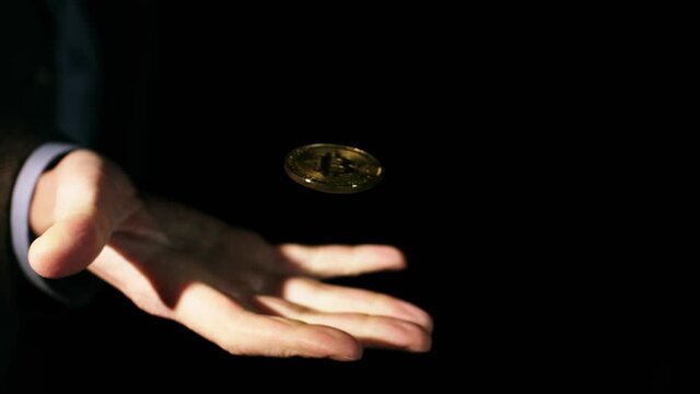 A man's hand opens a fist, and bitcoin appears on the palm, spinning in the air, close-up. Launch Bitcoin into circulation.