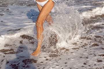 Fototapeta premium woman run in a white bathing suit and hat sunglasses on an empty sandy beach