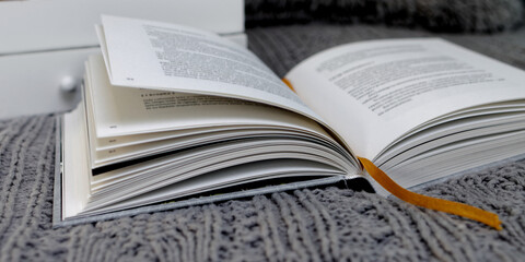 Obraz premium Open book closeup in cozy winter reading setup in bed with gray blanket.