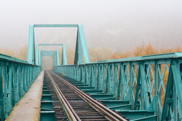 Old bridge with train tracks on a foggy day