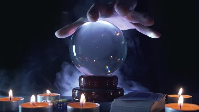 Hand of magician or fortuneteller above glass ball. Oracle is predicting the future.