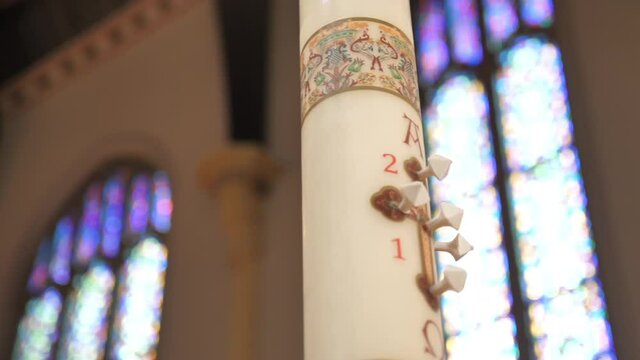 Paschal Candle With Alpha and Omega Symbols in Interior of Catholic Church Close Up Slow Motion Parallax Shot