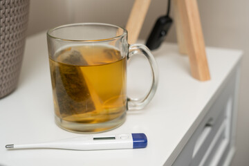 Close-up of hot tea mug and digital thermometer as cold concept
