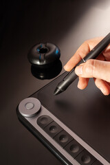 Graphic designer working with graphics tablet. Dark background.