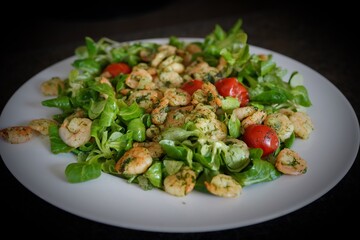green salad with shrimps and cherry tomatoes on a white plate