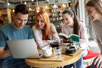 Group of university students hangout in college cafe library and preparing for lecture.	