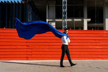 Confident businessman wearing superhero cape in the city