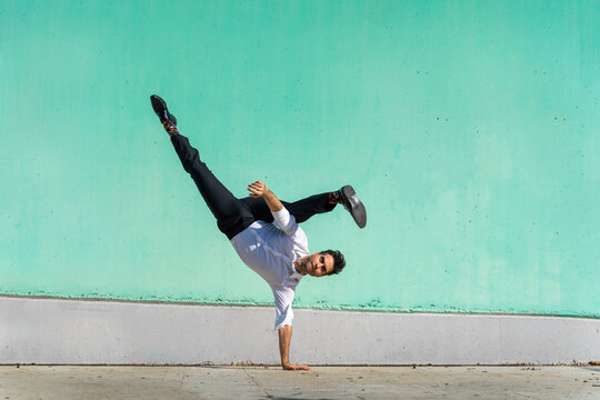 Businessman doing handspring in front of green wall - Powered by Adobe