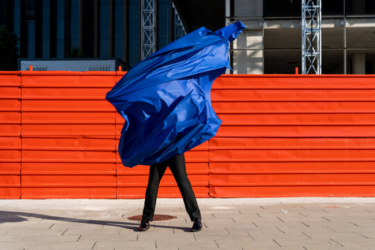 Anonymous man covered by blue cape